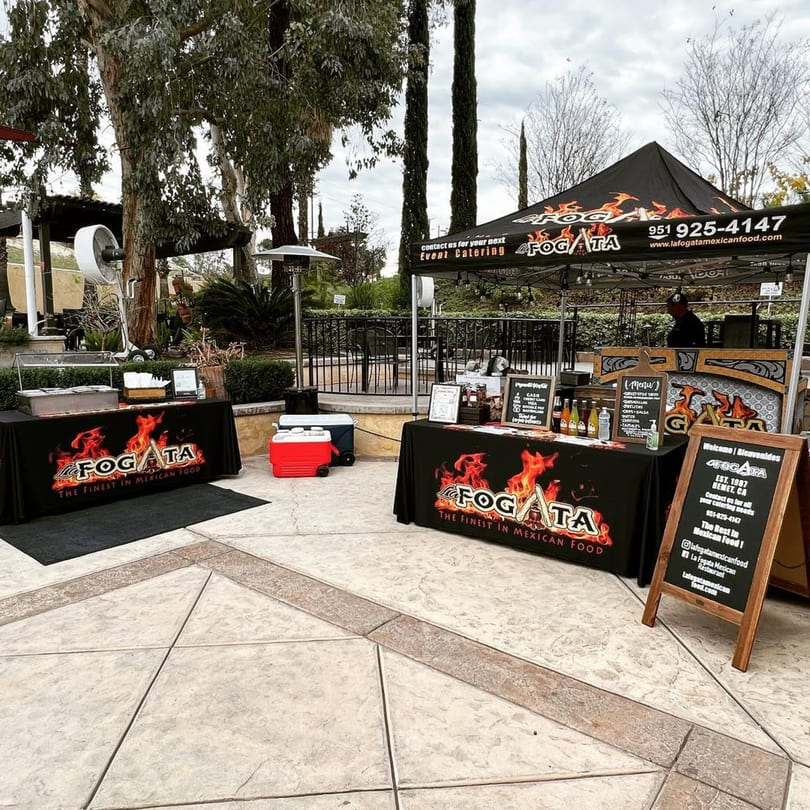 La Fogata Mexican Restaurant catering setup outdoors with black tents, tables, and menu boards.