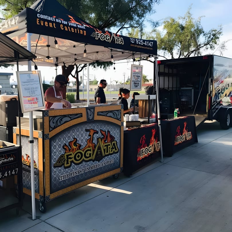 La Fogata Mexican Restaurant's catering setup with tents, food stands, and a trailer outdoors.
